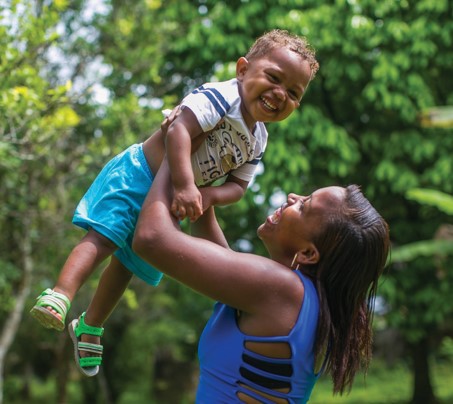 Mãe segura bebê no alto, ambos sorriem