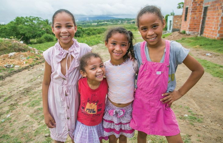 Quatro meninas se abraçam e sorriem