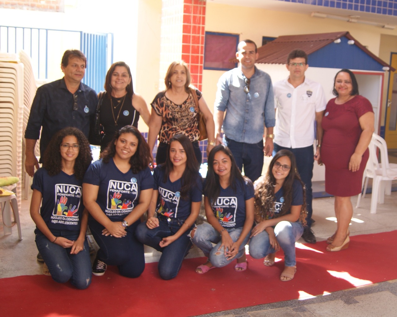 Pessoas posam para a foto - entre elas hÃ¡ adolescentes com uma camisa na qual estÃ¡ escrito NUCA e adultos